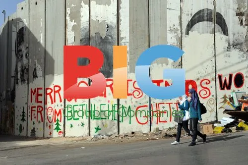 Palestinian women pass Bethlehem graffiti