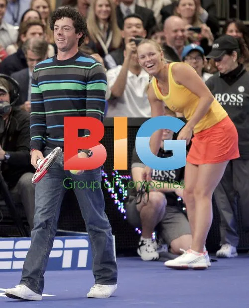 Caroline Wozniacki watches Rory McIlroy hit tennis ball