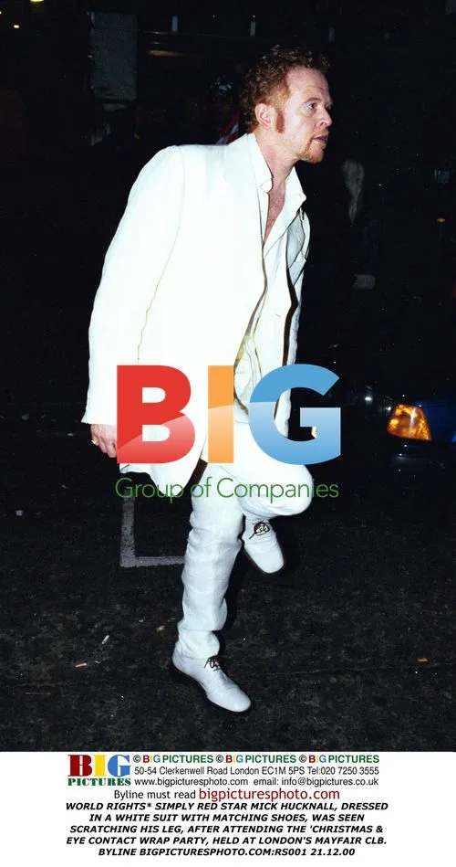 Mick Hucknall Scratches Leg in White Suit