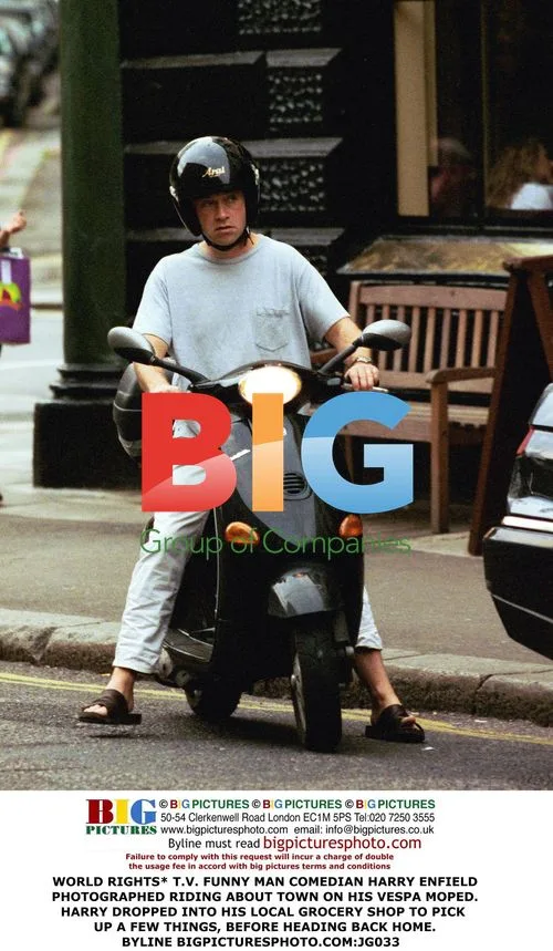 Harry Enfield rides Vespa in town