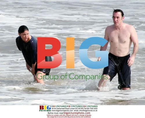 John Cusack frolics on beach with mystery woman