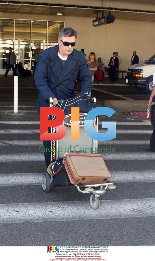 Alec Baldwin carries own luggage at LAX